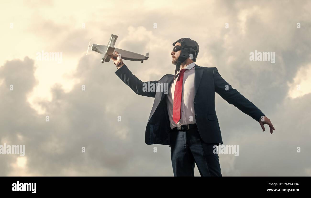 businessman in suit and pilot hat launch plane toy on sky background. aspirations Stock Photo