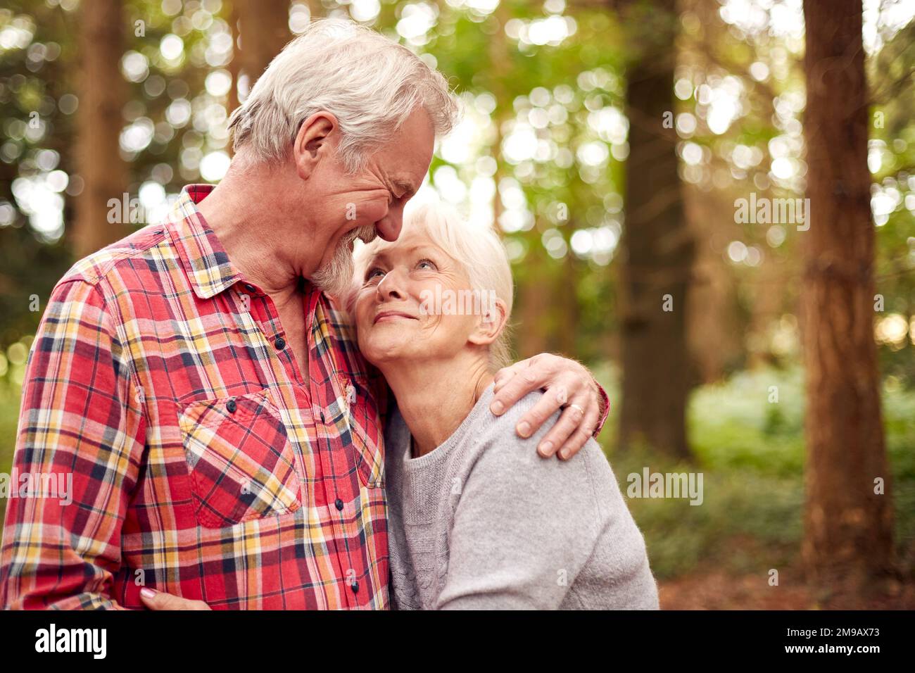 Loving Retired Senior Couple Hugging On Walk In Woodland Countryside Together Stock Photo