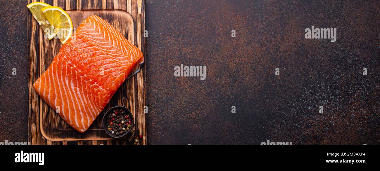 Fresh raw salmon fillet on wooden kitchen cutting board with seasonings ...