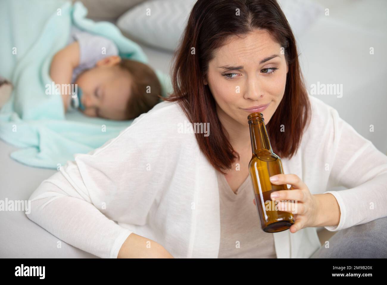 woman drinking alcohol next to her baby Stock Photo