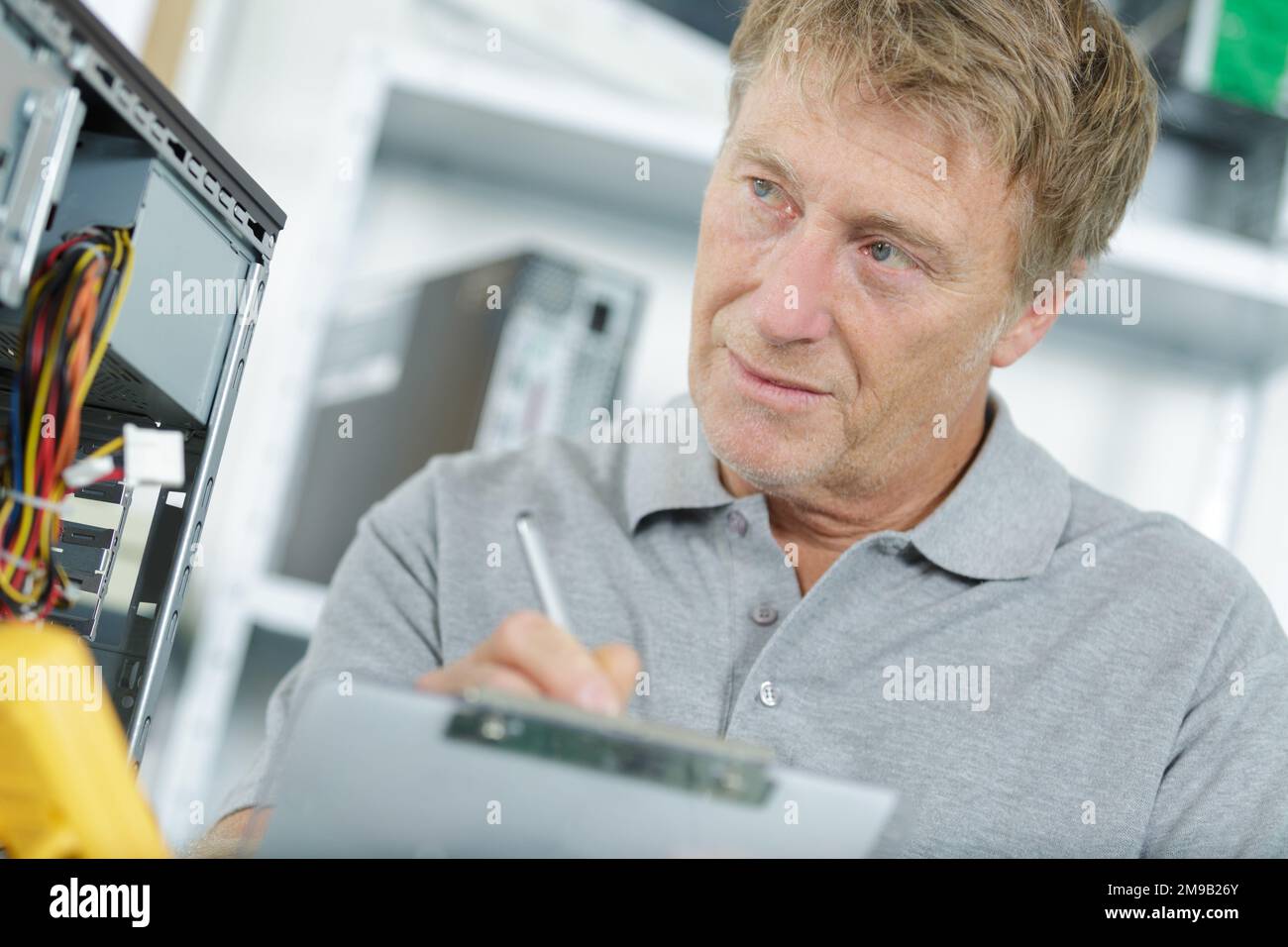engineering holding clipboard next to pc Stock Photo