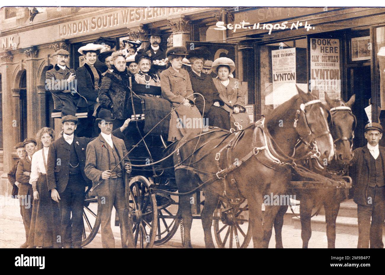The coach and horses are outside the London South Western Railway offices in Lynton. A poster on the wall offers excursions by Sam Colwill. Driver beside the coach has a whip and a smart man with velvet collar overcoat, flat hat and pipe might just be Sam himself. The railway closed in 1922. Stock Photo