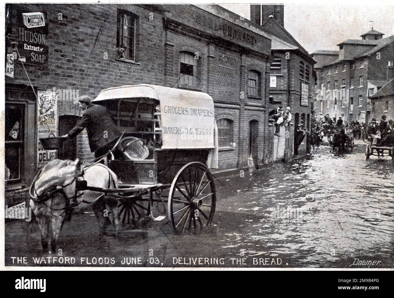 The flood is in Watford and someone in an upper story of a house has a basket hanging on a rope and the baker in the horse and cart is putting things in it. Stock Photo