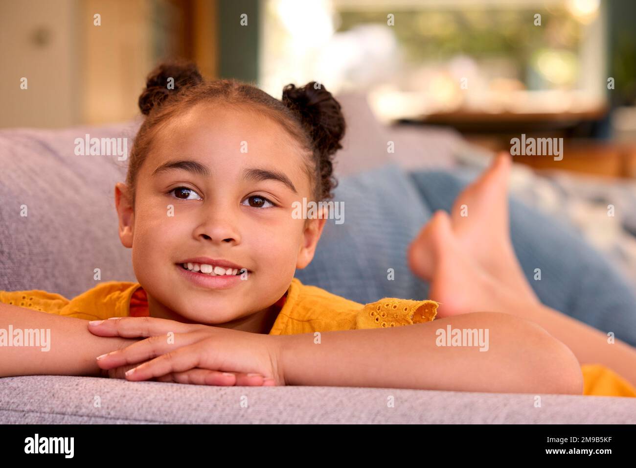 Portrait Of Smiling Girl Relaxing Lying On Sofa At Home Stock Photo - Alamy