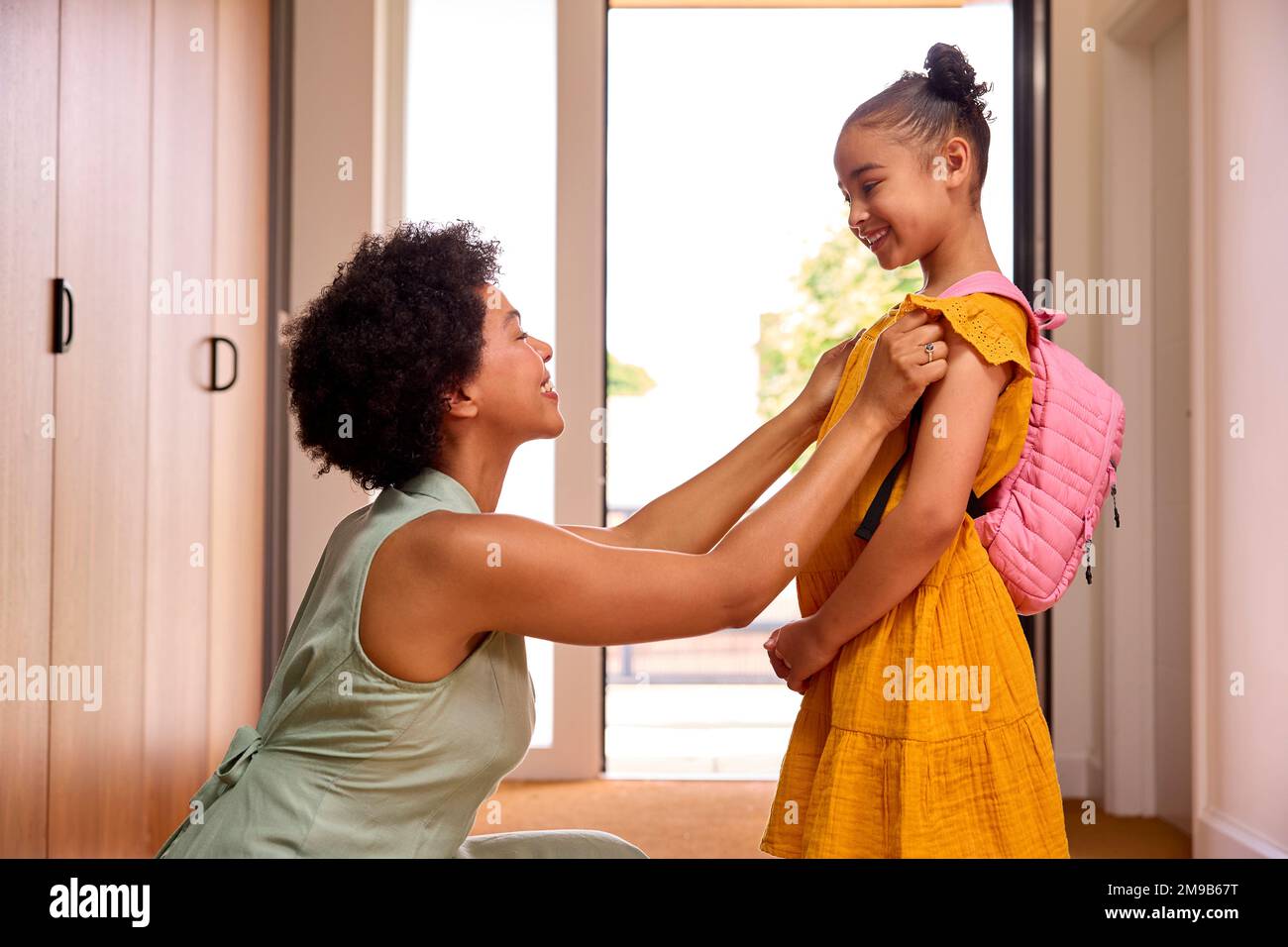 Mother At Home Helping Daughter Getting Ready To Go To School Stock Photo