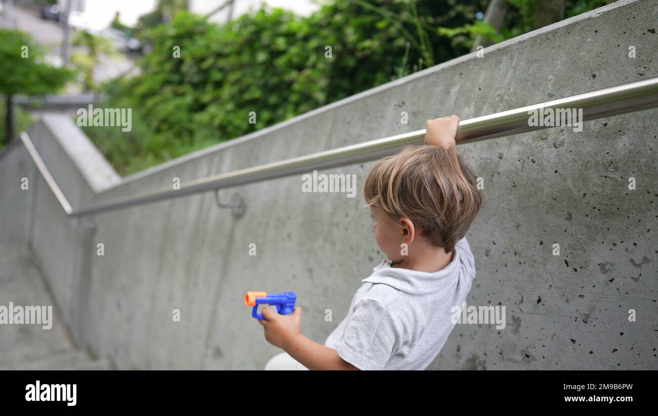 Toddler holding on handrail going down the stairs. Child stepping down