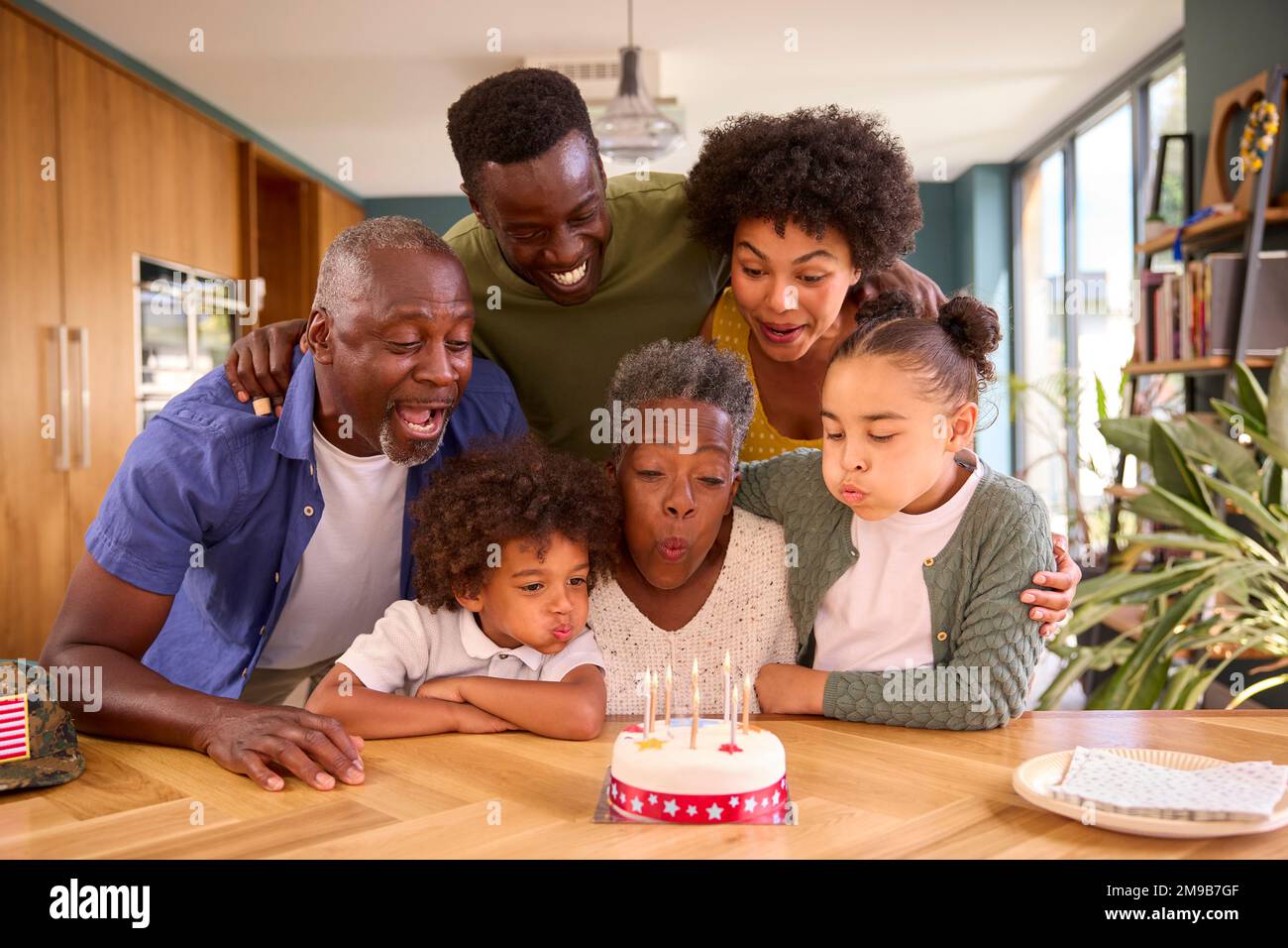 Multi-Generation Family With Military Father Celebrating Birthday With Cake Ay Home Stock Photo