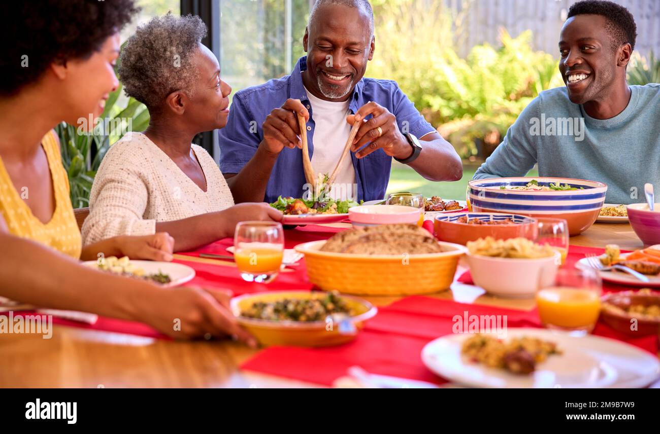 Parents With Adult Offspring Sitting Around Table At Home Enjoying Meal Together Stock Photo