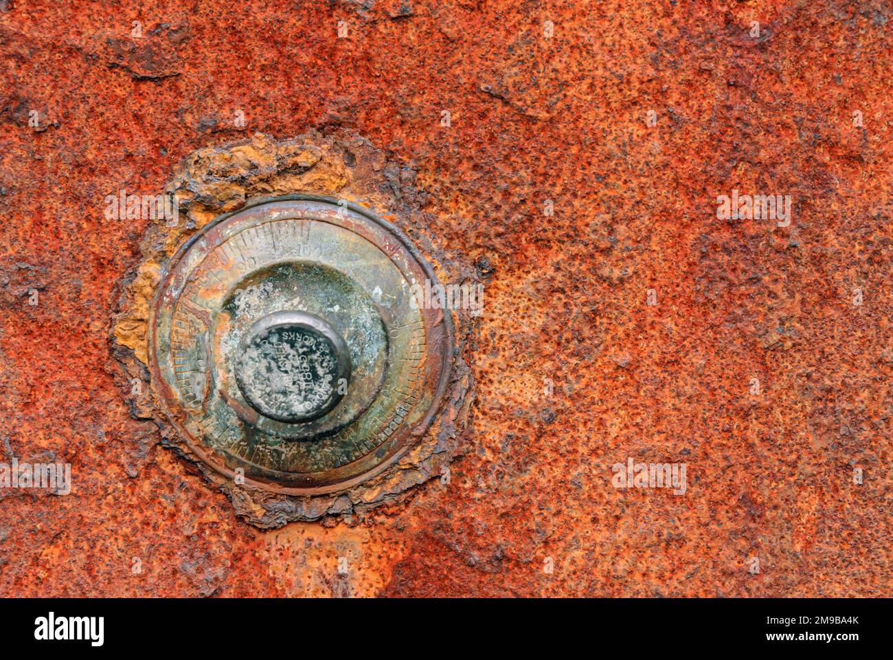 Rusted combination lock on a red rusty safe door Stock Photo