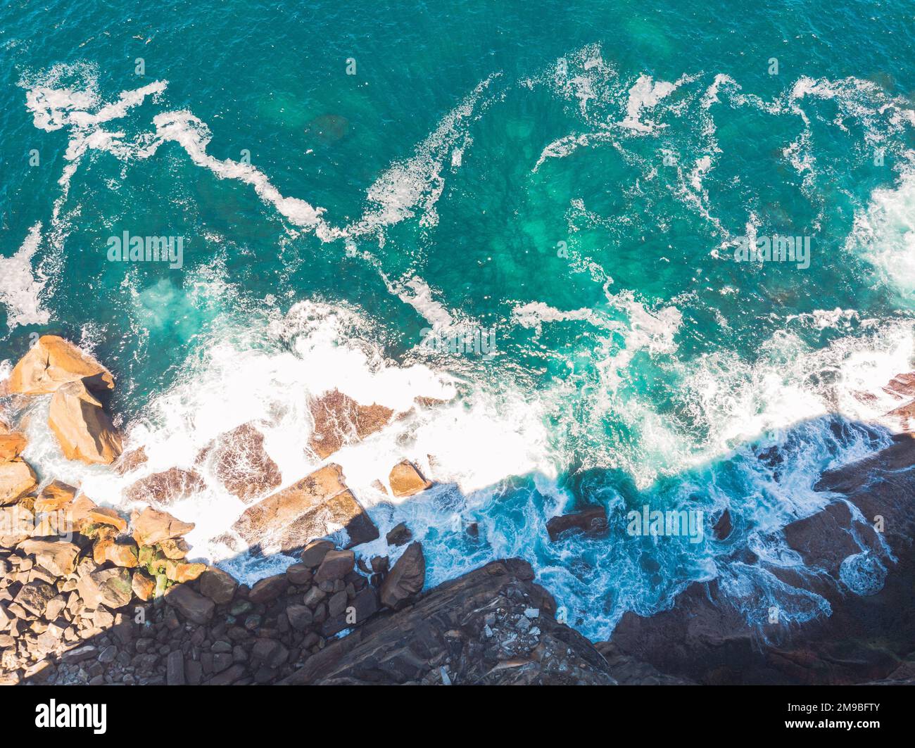 A scenic aerial top view of ocean waves hitting the rocky cliff at Wedding Cake Rock beach in Sydney Stock Photo