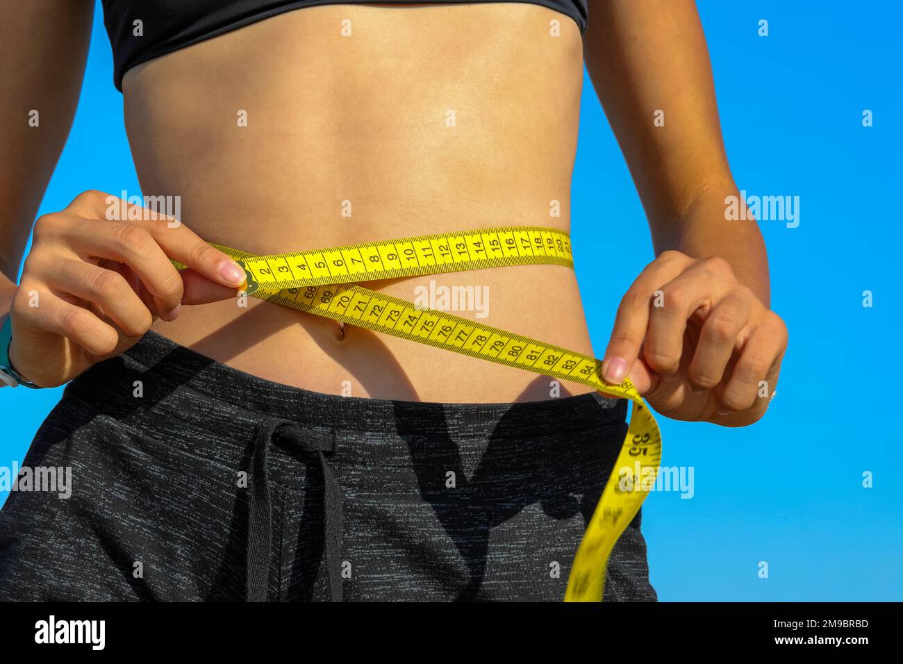 Premium Photo  Close up of slim woman measuring her waist's size with tape  measure.