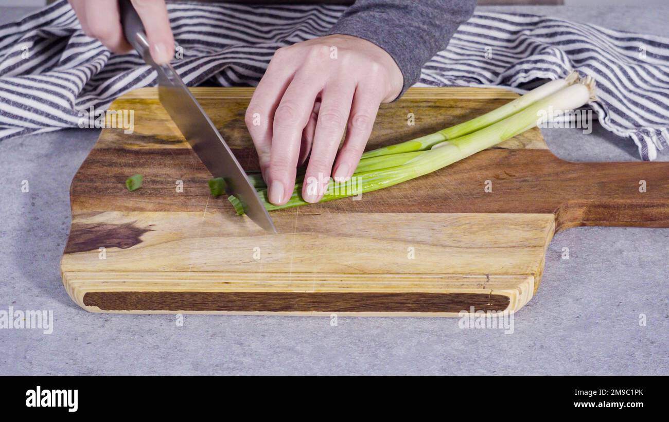 Cutting organic green onions on a wood cutting board Stock Photo - Alamy