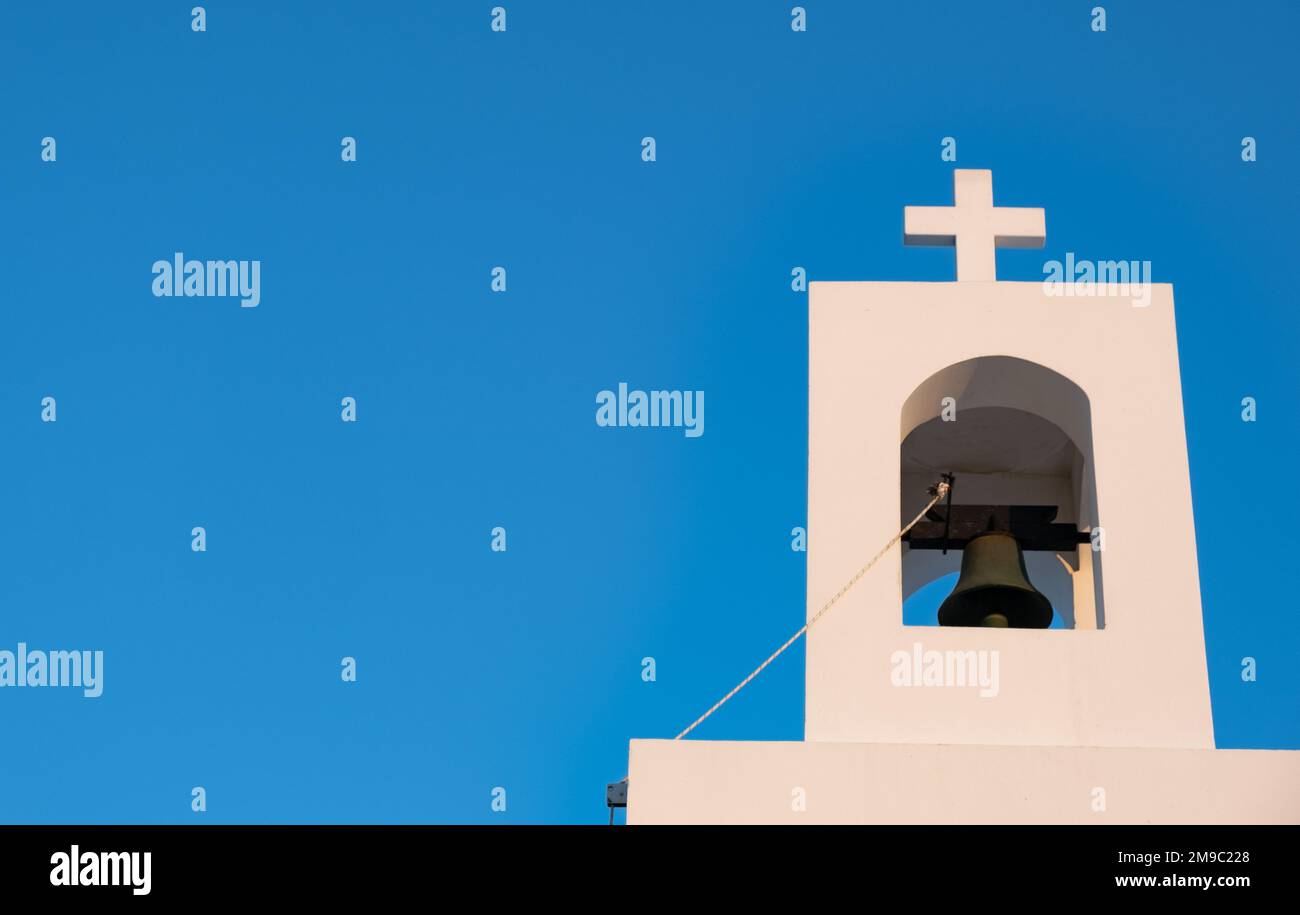 White christian belfry with cross on a greek church against blue sky. Faith and religion temple Stock Photo