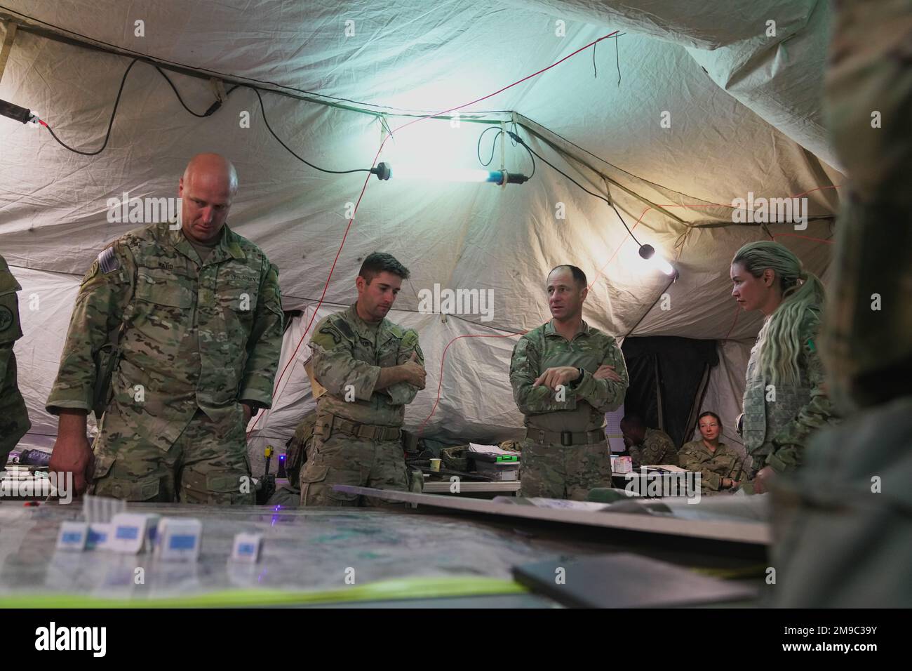 U.S. Army Col. Kevin Bradley, Regimental Commander of the 3d Cavalry Regiment, (middle right) discusses operational plans to his team in the Regimental Tactical Operations Center during a training rotation to the National Training Center, Fort Irwin, California, May 15, 2022. The regiment trained on logistics, attacking, defending and sustainment operations over the span of a few hundred kilometers during the month-long training. Stock Photo