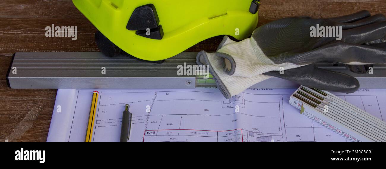 work table where there are drawings of land plans and building projects, on elect and work gloves. Worktable of a construction engineer on a construct Stock Photo
