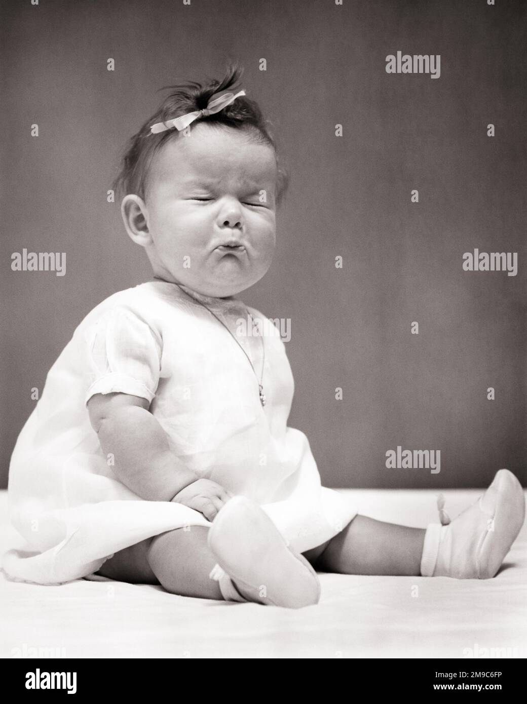 1940s BABY GIRL SITTING UP WEARING DRESS BOW IN HER HAIR A NECKLACE POUTING EYES CLOSED ABOUT TO CRY BAD TASTE OR SOUR TASTE - b17869 HAR001 HARS FACIAL ANGER FEAR COMMUNICATION COMIC INFANT WORRY LIFESTYLE FEMALES STUDIO SHOT MOODY TEARS HOME LIFE COPY SPACE FULL-LENGTH CRY EXPRESSIONS TROUBLED B&W CONCERNED SADNESS HUMOROUS WEEPING POUTING BOOTIES COMICAL TASTE BAWLING UP MOOD SOBBING FUNNY FACE GLUM COMEDY OR SCRUNCHING BAD TASTE JUVENILES MISERABLE SCRUNCHED SOUR BABY GIRL BLACK AND WHITE CAUCASIAN ETHNICITY EYES CLOSED HAR001 OLD FASHIONED SITTING UP Stock Photo