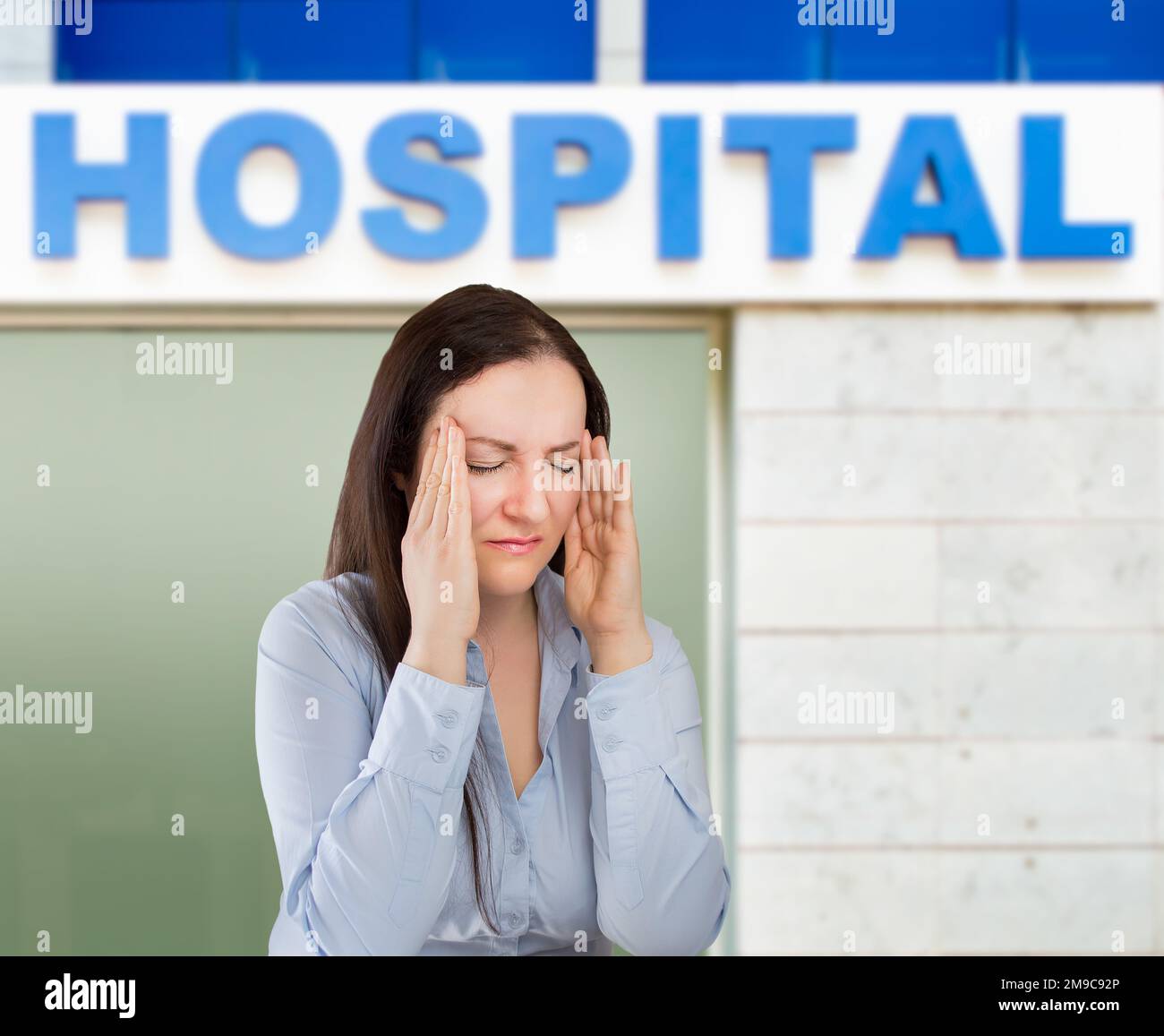 woman battles a headache next hospital building Stock Photo