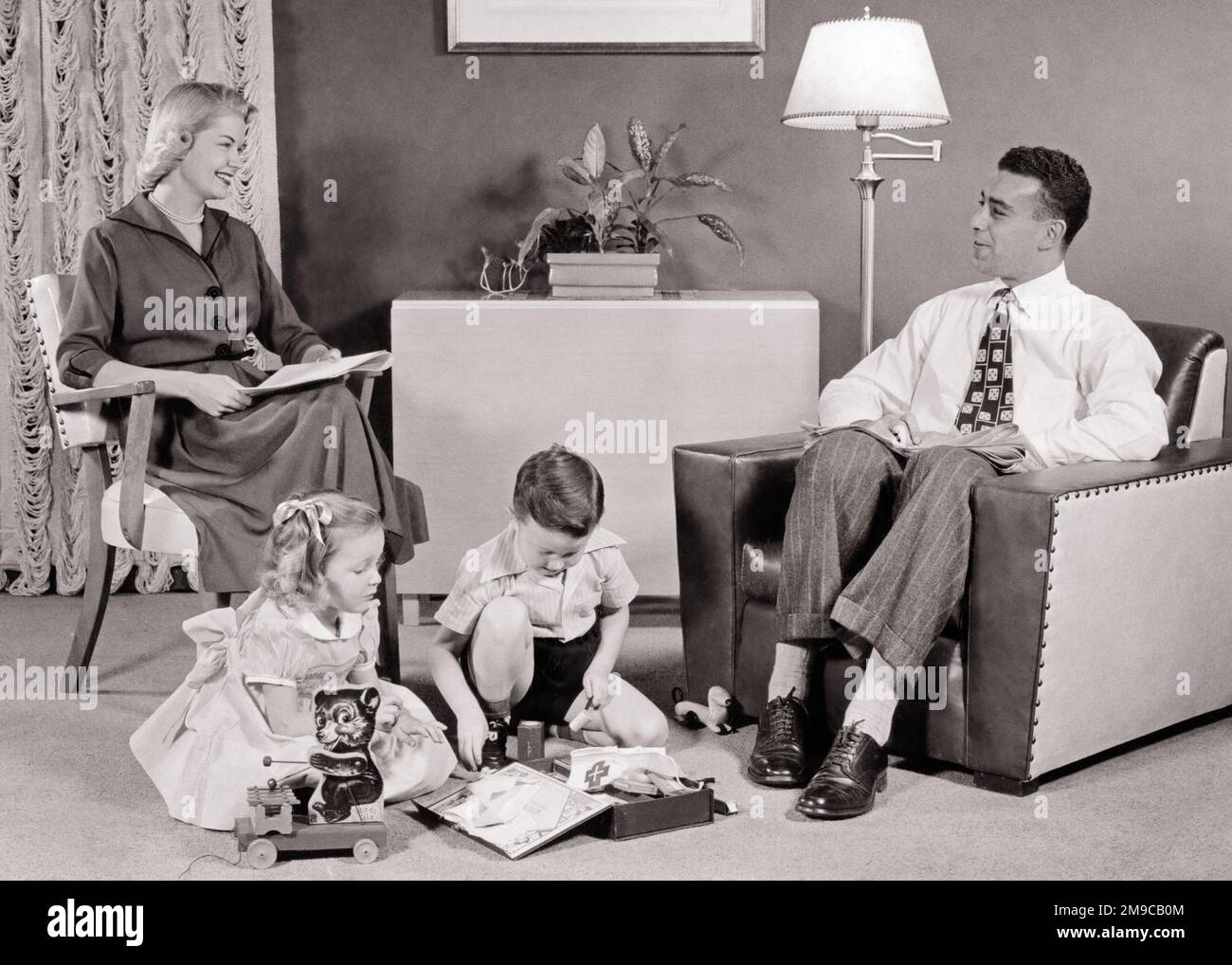 1950s FATHER MOTHER SITTING TOGETHER WITH SON DAUGHTER PLAYING ON RUG IN LIVING ROOM FURNISHED IN MID-CENTURY MODERN STYLE - j171 HAR001 HARS INDOORS NOSTALGIC PAIR 4 SUBURBAN URBAN MOTHERS OLD TIME NOSTALGIA BROTHER OLD FASHION SISTER 1 JUVENILE COMMUNICATION SECURITY RUG FAMILIES JOY LIFESTYLE SATISFACTION CELEBRATION FEMALES MARRIED BROTHERS SPOUSE HUSBANDS MODERN HOME LIFE FULL-LENGTH LADIES PERSONS INSPIRATION CARING MALES SERENITY SIBLINGS CONFIDENCE SISTERS FATHERS B&W PARTNER SUCCESS WIDE ANGLE DREAMS HAPPINESS LEISURE STRENGTH LIVING ROOM CHOICE DADS RECREATION INNOVATION PRIDE IN ON Stock Photo