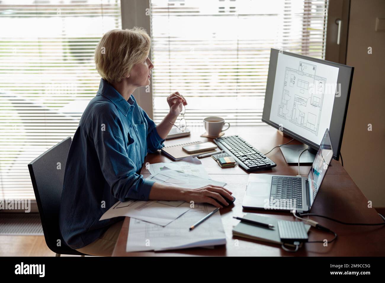Focused mature woman engineer constructor works on project from home office using computer Stock Photo