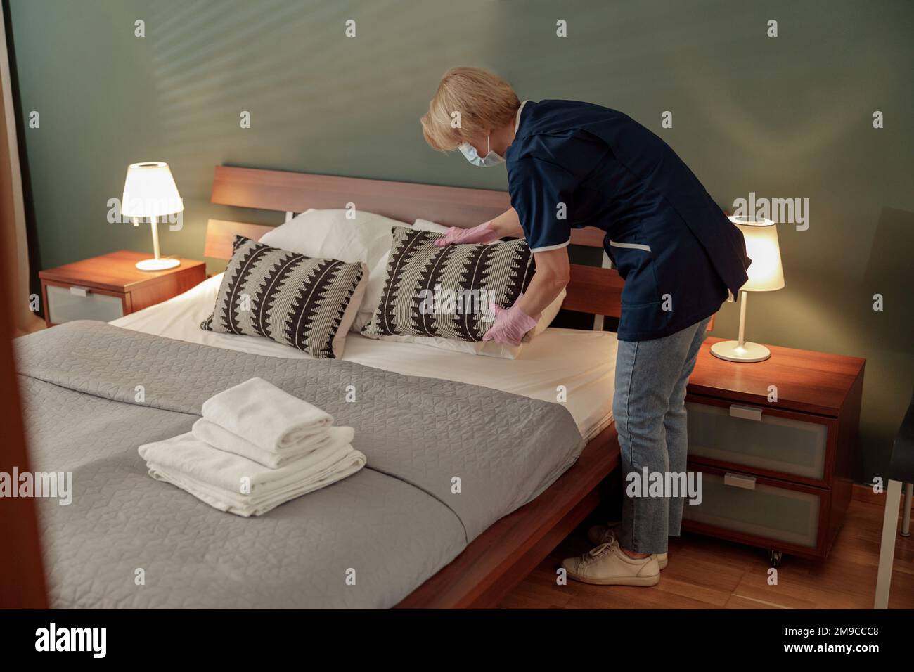 Cleaning lady doing housekeeping and making bed in hotel room. Cleaning