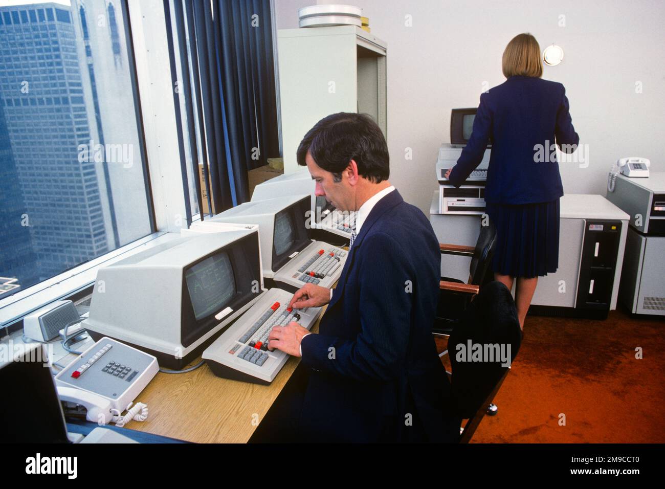 1980s MAN AND WOMAN WORKING IN COMPUTER OFFICE - ko1312 PHT001 HARS LADIES COMPUTERS PERSONS MALES PROFESSION EXECUTIVES SKILL SUIT AND TIE OCCUPATION SKILLS AND CAREERS MONITORS PROGRESS INNOVATION OCCUPATIONS HIGH TECH MONITOR SUPPORT COOPERATION MANAGERS MID-ADULT MID-ADULT MAN MID-ADULT WOMAN SOLUTIONS CAUCASIAN ETHNICITY COMPUTING OLD FASHIONED Stock Photo