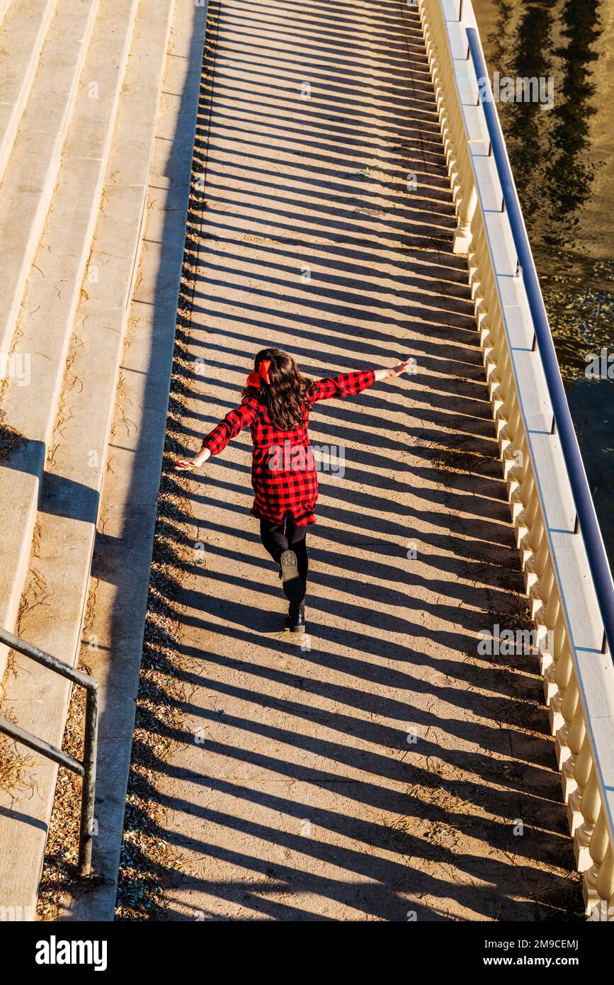 Young girl skipping happily along sunlit stone path; Fairmount Water Works; Philadelphia; Pennsylvania; USA Stock Photo