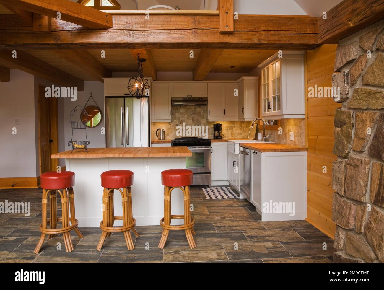 White wooden island with wood countertop and red leather and wood