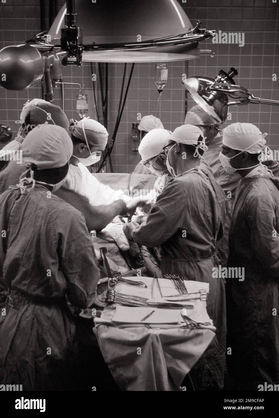 1950s ANONYMOUS SURGEONS DOCTORS NURSES ATTENDING SURGERY IN HOSPITAL OPERATING ROOM ALL IN STERILE GOWNS CAPS MASKS - m339 HAR001 HARS PHYSICIANS SURGEONS GOWNS OPERATING ROOM HEALTH CARE IMPAIRMENT OCCUPATIONS SURGEON TREATMENT HEALER CAPS HOSPITALS OPERATION PHYSICIAN PRACTITIONER FACILITY ANONYMOUS FACILITIES ATTENDING PROFESSIONALS BLACK AND WHITE CAUCASIAN ETHNICITY DISEASE HAR001 OLD FASHIONED Stock Photo