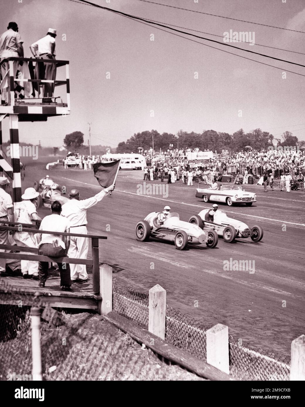1950s 100 MILE SPORTS CAR RACE AT THE LANGHORNE SPEEDWAY LANGHORNE PA USA FLAGMAN WAVING A FLAG OF WARNING - m676 HAR001 HARS STRATEGY AUTOS EXCITEMENT PA WARNING RISKY HAZARDOUS OCCUPATIONS PERIL PROFESSIONAL SPORTS UNSAFE AUTOMOBILES VEHICLES MILE JEOPARDY OFFICIALS RACEWAY COOPERATION LANGHORNE THRONG ATTENDANCE BLACK AND WHITE HAR001 OLD FASHIONED Stock Photo