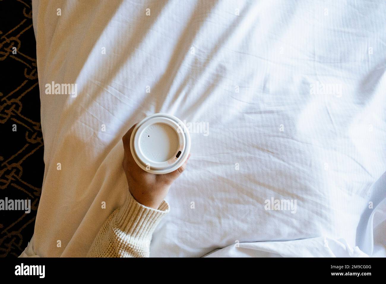Woman Holding Paper Cup of Coffee in Bed with Lipstick Stock Photo