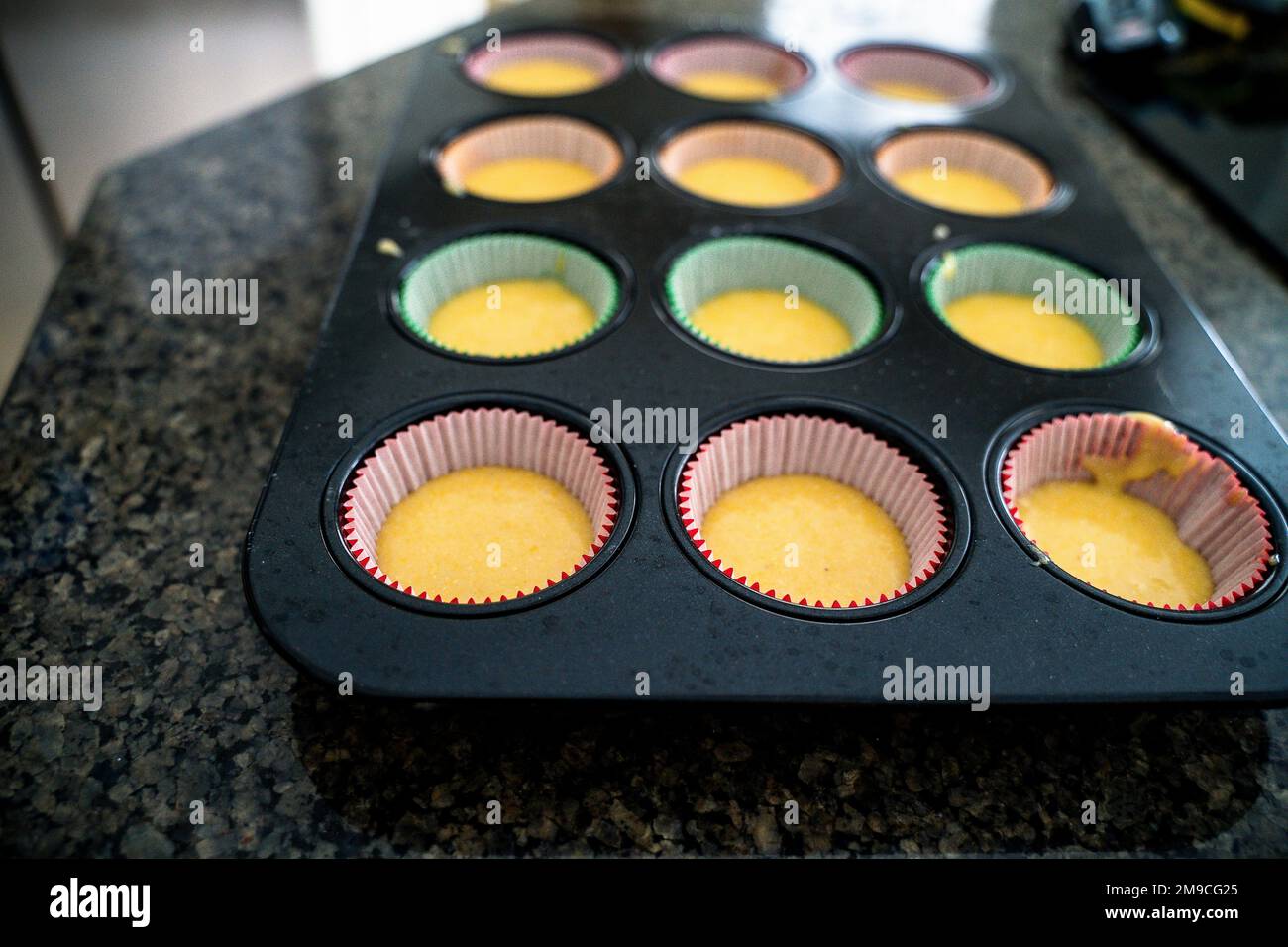 Cupcake Batter in Colored Liners on Countertop Stock Photo