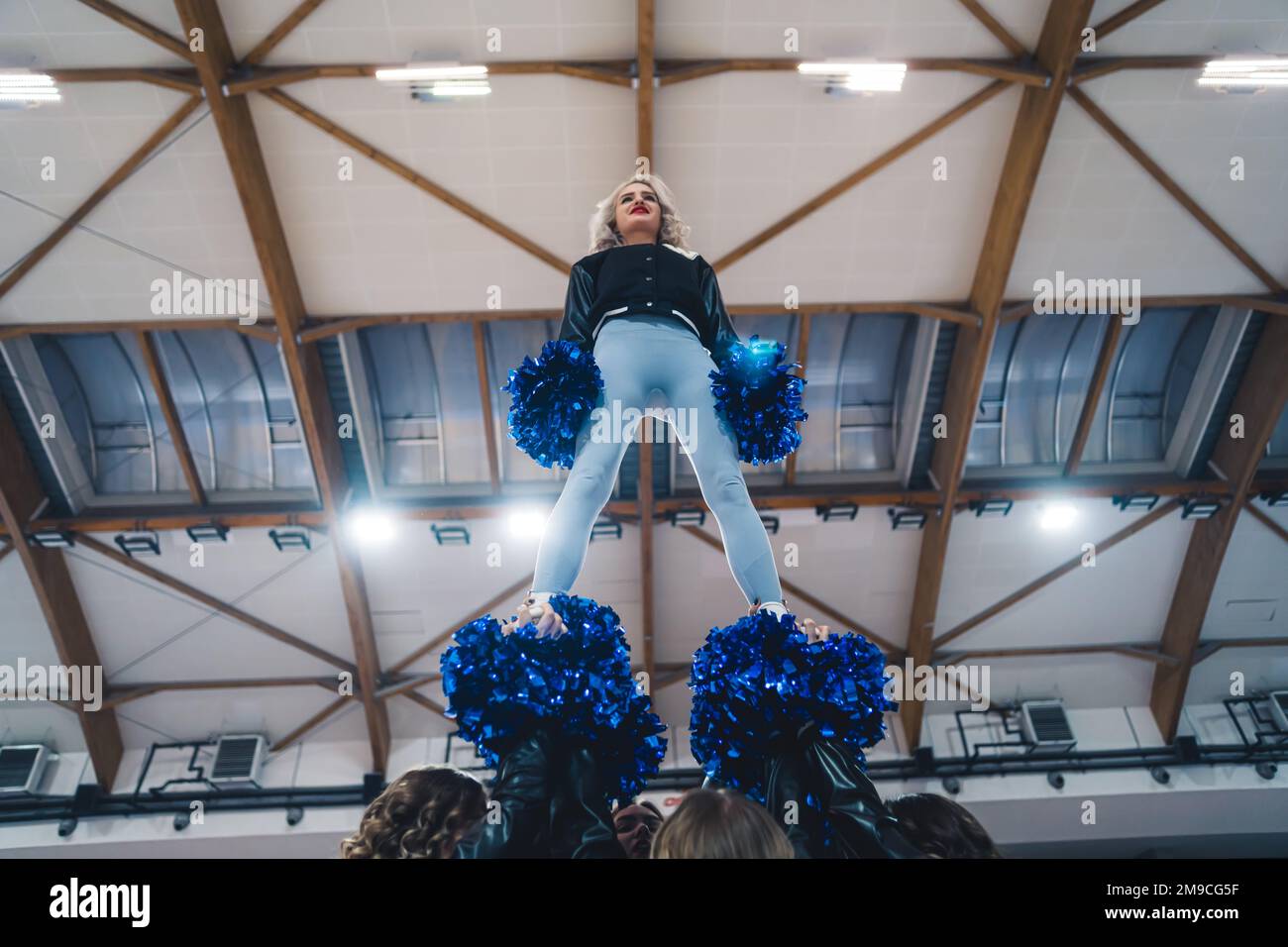 Lowangle shot of a cheerleader standing on the top of a pyramid. Sport