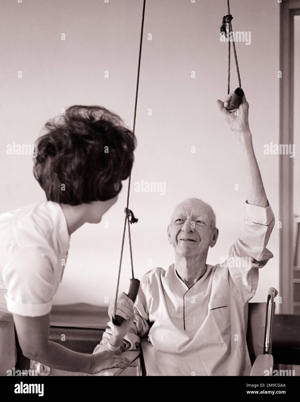 1960s NURSE PHYSICAL THERAPIST HELPING A SENIOR MAN WITH PULLEY EXERCISES TO REHAB HIS UPPER BODY AND SHOULDER STRENGTH - m8487 HAR001 HARS BALANCE NURSING SAFETY TEAMWORK LIFESTYLE ELDER FEMALES COPY SPACE HALF-LENGTH LADIES PERSONS INSPIRATION CARING MALES SENIOR MAN SENIOR ADULT PULLEY B&W GOALS HEALTHCARE SUCCESS ACTIVITY OCCUPATION PHYSICAL OLD AGE OLDSTERS PROVIDER OLDSTER PROVIDERS HIS PRACTITIONERS PROTECTION STRENGTH HEALING AND UPPER HEALTH CARE EXERCISES OCCUPATIONS ELDERS CONNECTION HEALER REHAB FLEXIBILITY HOSPITALS MUSCLES PRACTITIONER SUPPORT FACILITY FACILITIES COOPERATION Stock Photo