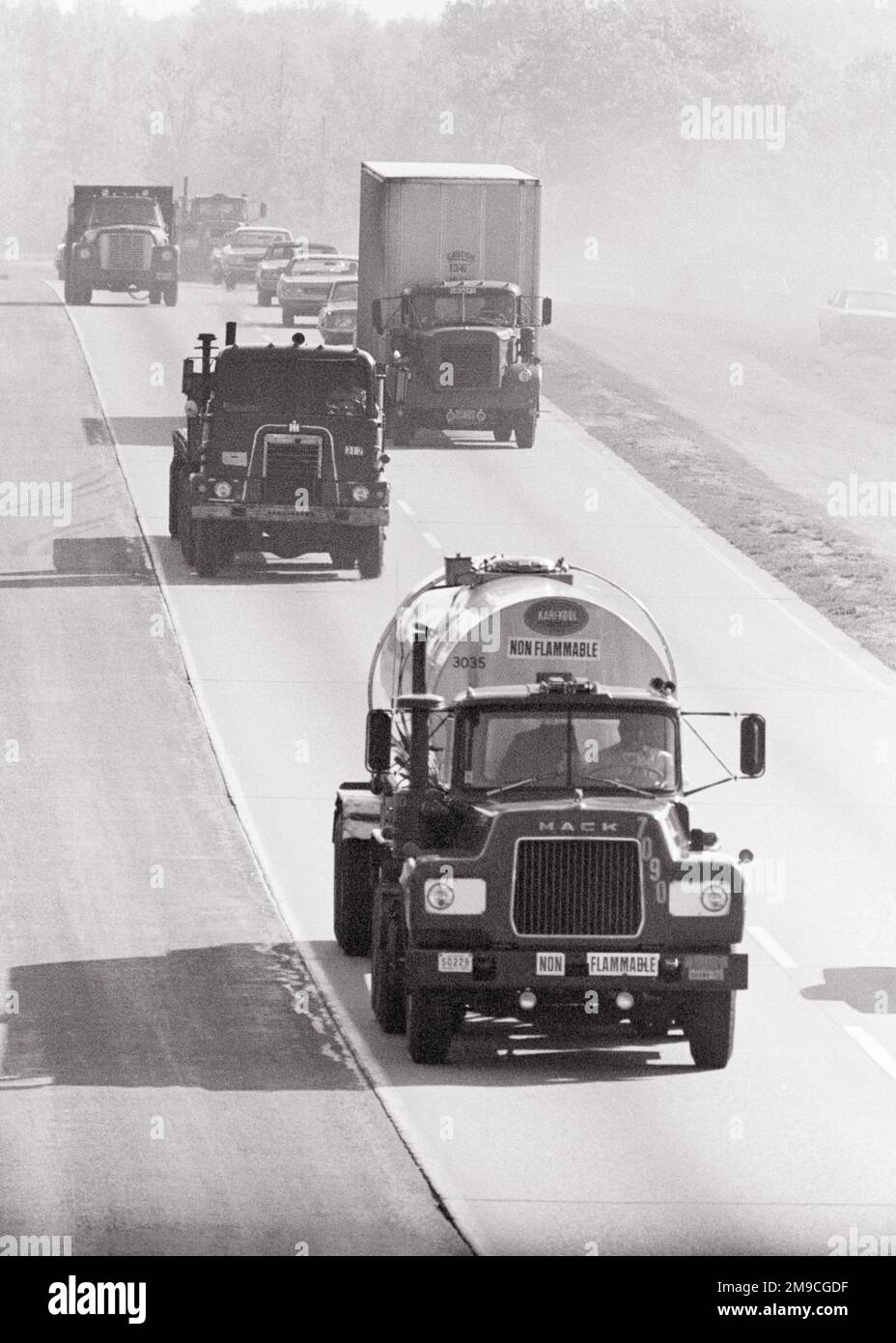 1970s LARGE TRUCKS AND SEMIS TRACTOR TRAILERS IN ONCOMING TRAFFIC ON DUAL LANE HIGHWAY - m8829 HAR001 HARS AND AUTOS HAULING DIRECTION ON OCCUPATIONS CONCEPTUAL DUAL AUTOMOBILES DELIVER SUPPORT VEHICLES ONCOMING CARRIERS TRACTOR TRAILERS COMMERCE DEMAND HAULAGE ROADS SEMI SHIPPING SUPPLY TRUCKING BLACK AND WHITE HAR001 HIGHWAYS OLD FASHIONED TRADE GOODS Stock Photo