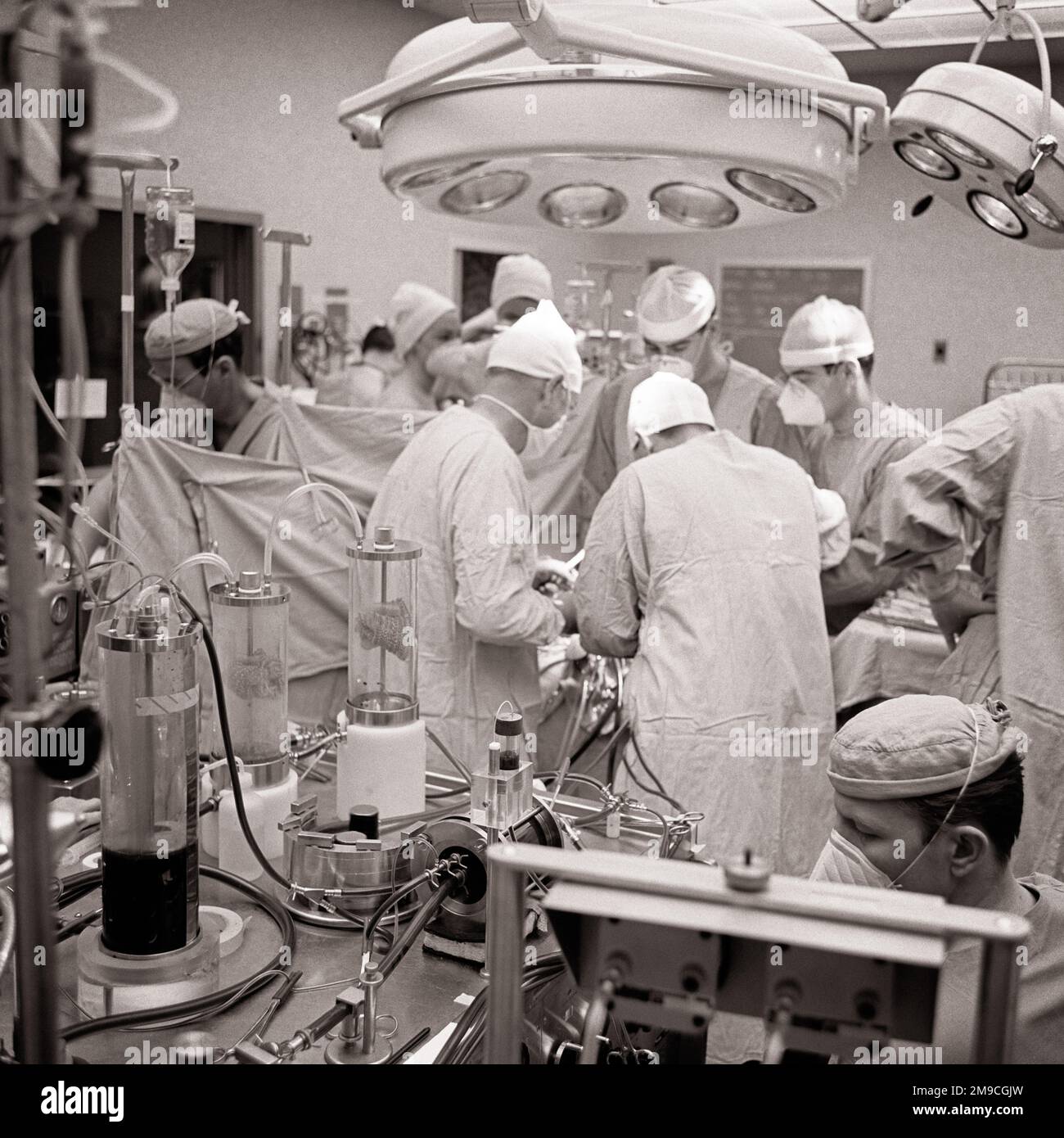 1970s SURGEON & ATTENDANT DOCTORS NURSES TECHNICIANS PERFORMING OPEN HEART SURGERY WITH THE USE OF A HEART LUNG MACHINE - m9054 HAR001 HARS PROVIDER PROVIDERS PRACTITIONERS STERILE HEALING SURGICAL PHYSICIANS SURGEONS INNOVATION OPERATING ROOM HEALTH CARE OPPORTUNITY OCCUPATIONS SURGEON HIGH TECH HEALER HOSPITALS OPERATION PHYSICIAN PRACTITIONER FACILITY TECHNICIANS FACILITIES ATTENDANT COOPERATION CREATIVITY PRECISION PROFESSIONALS SOLUTIONS USE & BLACK AND WHITE CAUCASIAN ETHNICITY HAR001 LUNG OLD FASHIONED Stock Photo