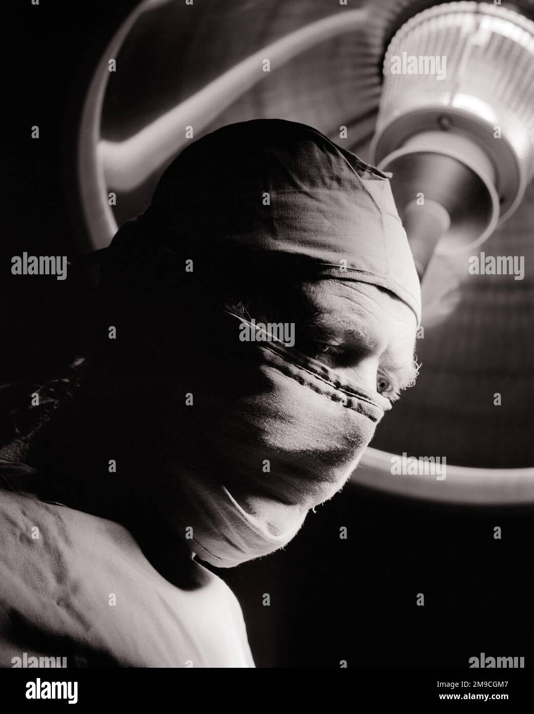 1970s MAN HOSPITAL SURGEON WEARING STERILE OPERATING ROOM CAP GOWN MASK UNDER AN O.R. LIGHT - m9091 HAR001 HARS MIDDLE-AGED B&W MIDDLE-AGED MAN HEALTHCARE SURGERY SKILL OCCUPATION SKILLS OPERATING HEAD AND SHOULDERS PROVIDER PROVIDERS PRACTITIONERS STERILE HEALING SURGICAL KNOWLEDGE PHYSICIANS POWERFUL SURGEONS OPERATING ROOM HEALTH CARE AUTHORITY OCCUPATIONS SURGEON HEALER CONCEPTUAL OPERATION PHYSICIAN PRACTITIONER SCRUBS SINCERE SOLEMN FOCUSED INTENSE O.R. PROFESSIONALS BLACK AND WHITE CAREFUL CAUCASIAN ETHNICITY EARNEST HAR001 INTENT OLD FASHIONED Stock Photo