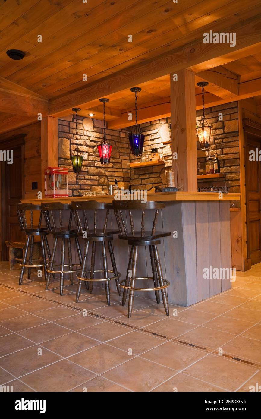 Fully equipped grey wooden bar with antique brown wooden bar stools in