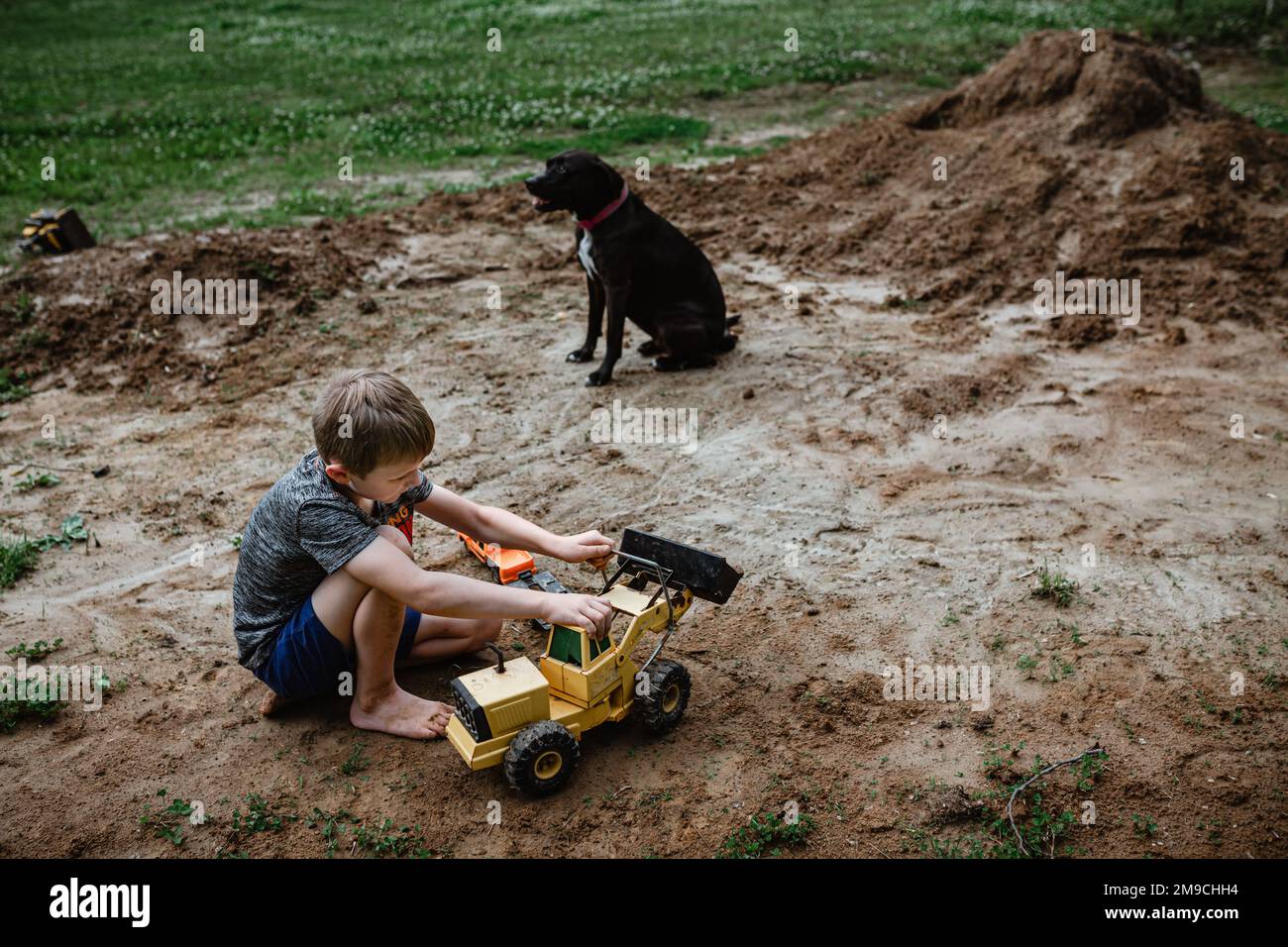 Boy playing tractors in dirt in yard at home Stock Photo - Alamy