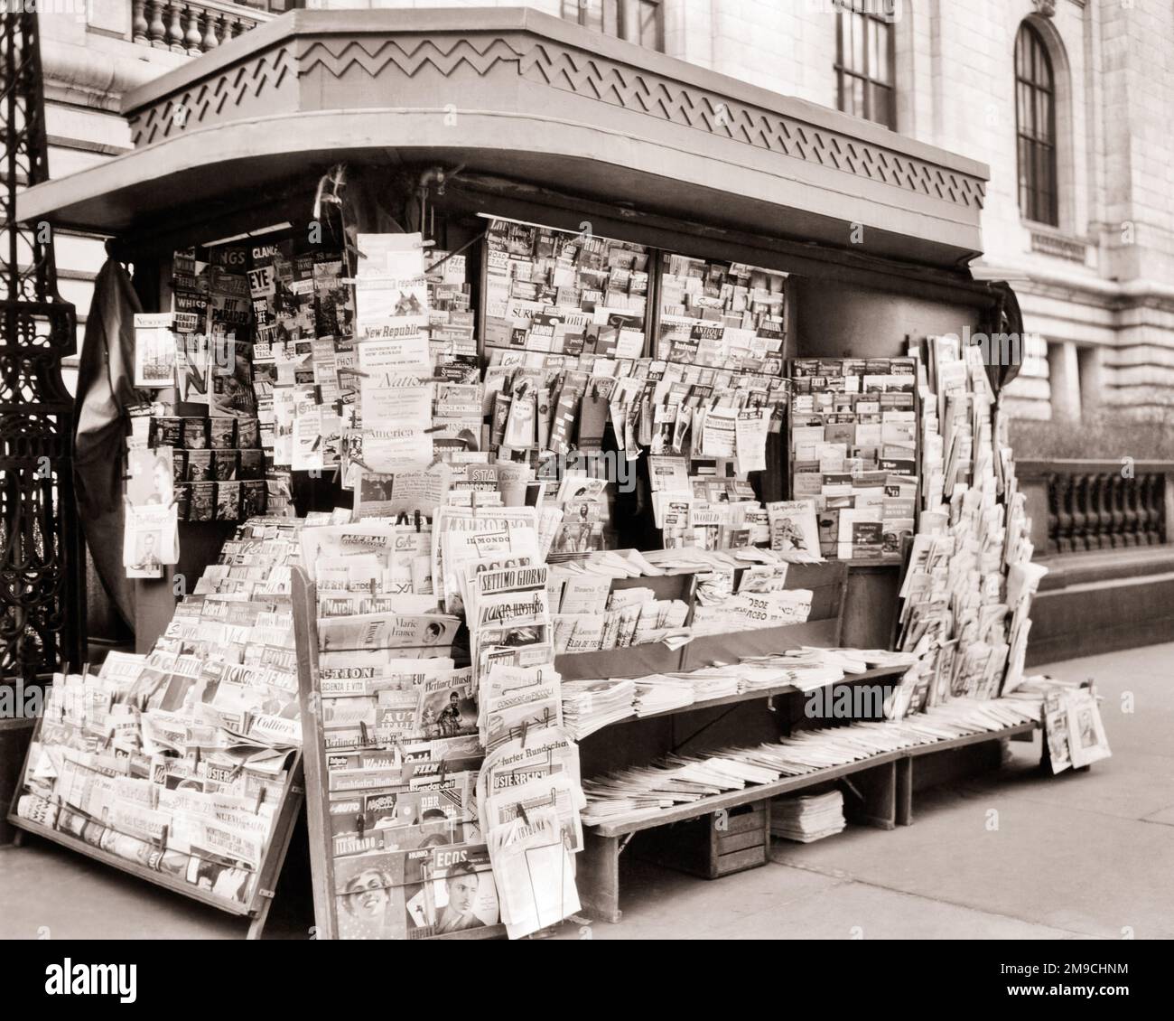 1950s INTERNATIONAL NEWSPAPERS AND MAGAZINES ON SALE AT SIDEWALK NEWSSTAND ON 42ND STREET AND FIFTH AVENUE NEW YORK CITY NY USA - r2347 HAR001 HARS EXTERIOR NEWSSTAND DISTRIBUTION LOCAL MAGAZINES NYC OCCUPATIONS CONCEPTUAL NEW YORK SMALL BUSINESS STILL LIFE CITIES MATERIALS VARIETY NEW YORK CITY KIOSK CREATIVITY IDEAS WORLDWIDE 42ND STREET ARRAY BLACK AND WHITE HAR001 INTERNATIONAL OLD FASHIONED PRINTED Stock Photo