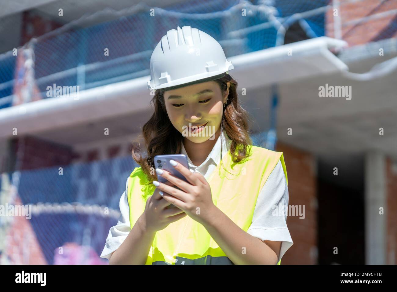 female architect looking at blueprints on her smartphone Stock Photo