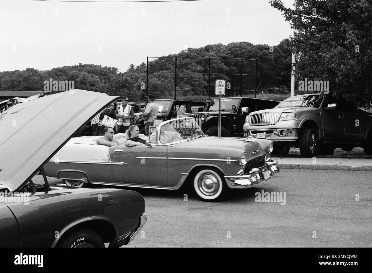 A vintage convertible Lincoln automobile with three passengers drives by at a car show in Essex