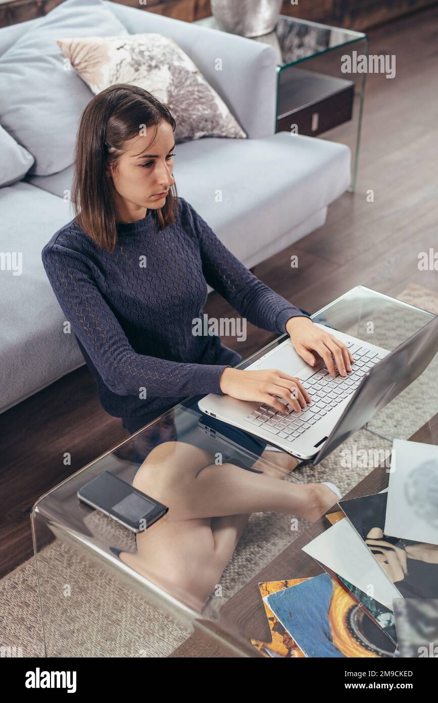 Woman sitting on the floor at home using laptop computer Stock Photo