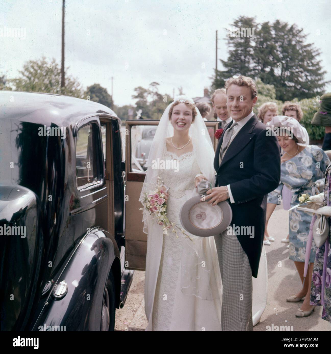 The newlyweds smiling happily as they get into the car to go to the wedding reception. Stock Photo