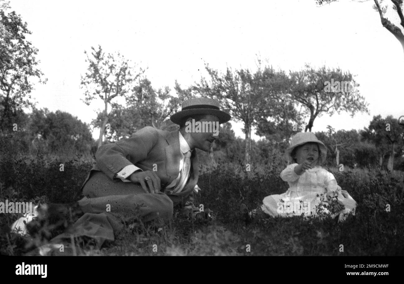 A father sits in a field with his son Stock Photo