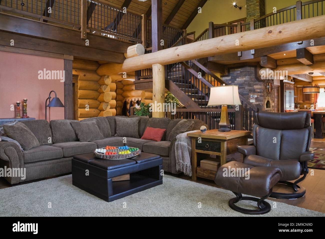 Living room with dark grey sectional sofa, brown leather armchair with ottoman and view of brown