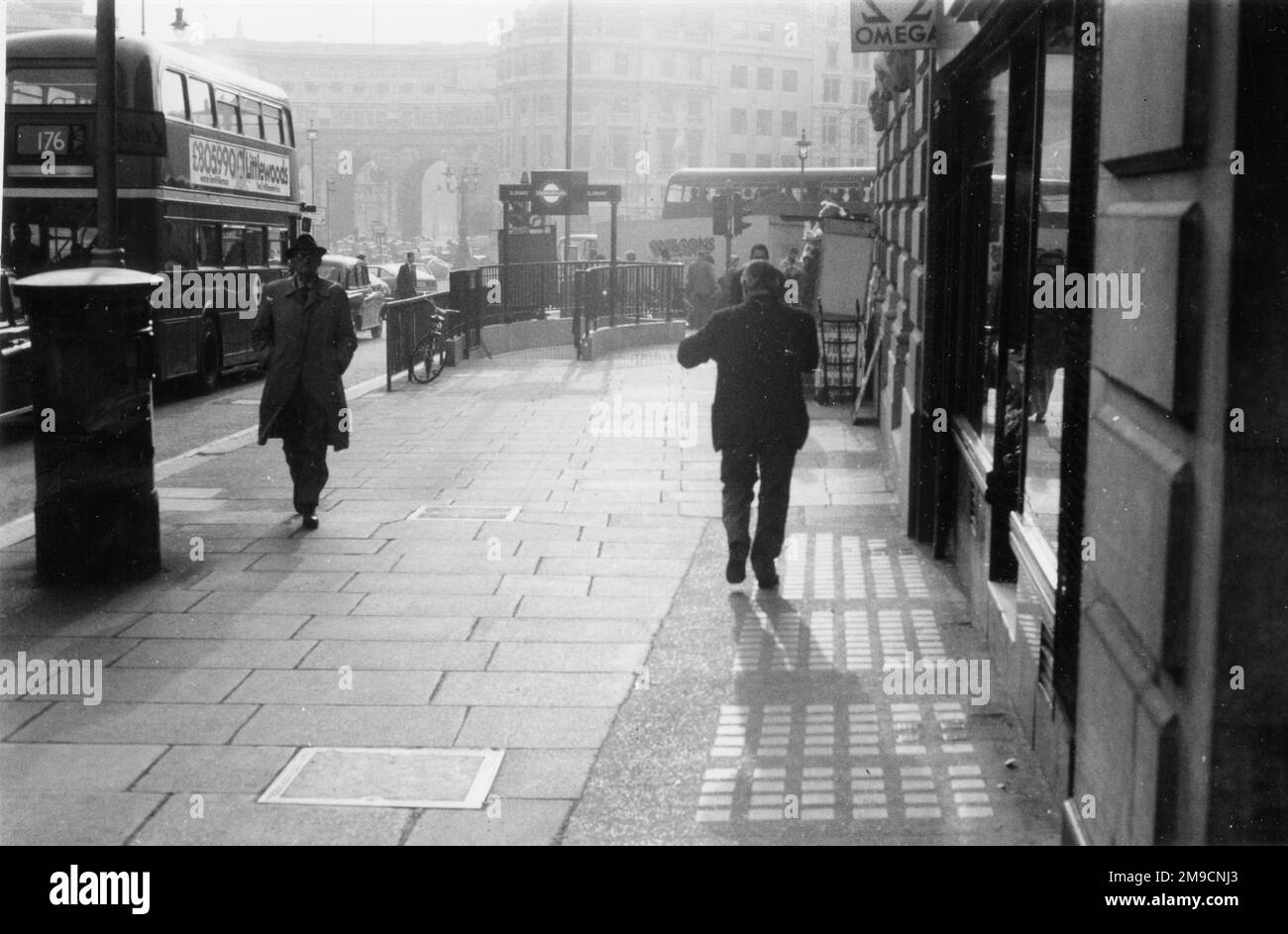 Pedestrians walking along the pavement at the very western end of The Strand, London, close to Trafalgar Square. Admiralty Arch can be seen in the background. Stock Photo
