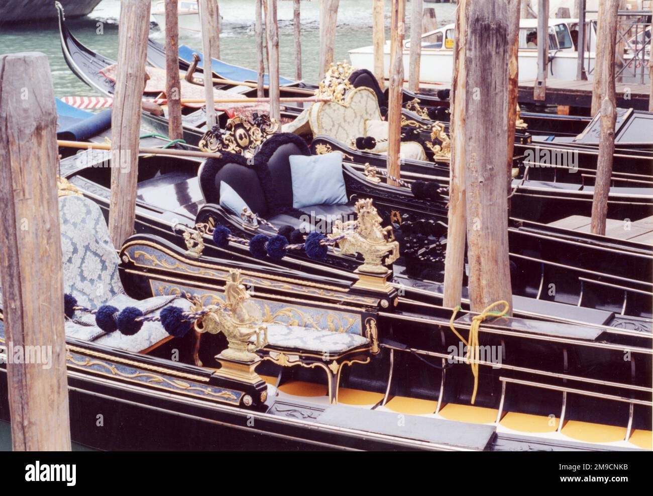 A row of gondolas moored on a canal in Venice, showing details of their ornate furnishings. Stock Photo