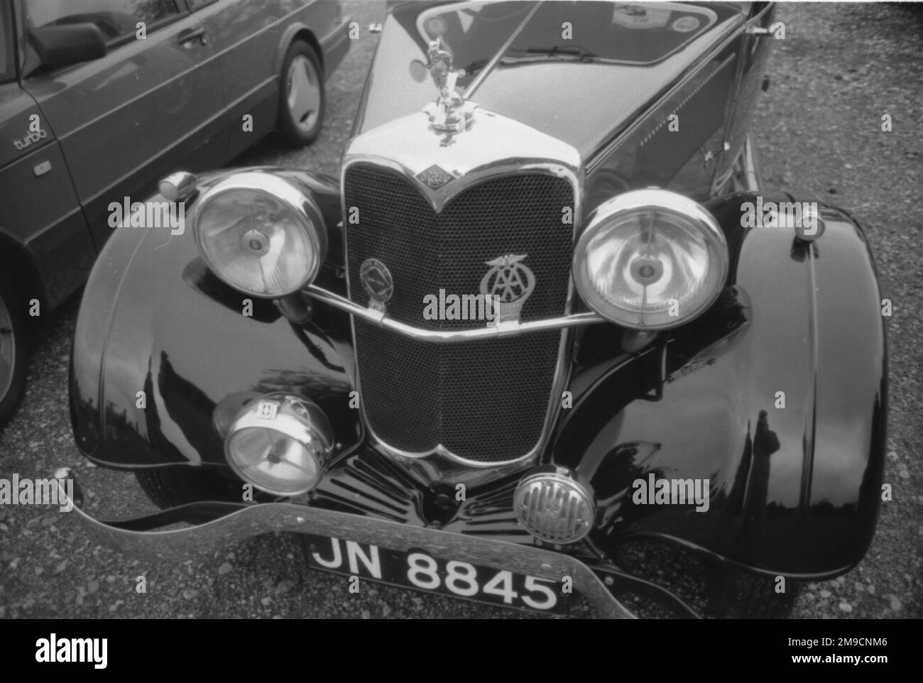 The front end of a Riley Sports car with elaborate chrome mascot, AA Badge, large headlamps and wide front wings. Stock Photo