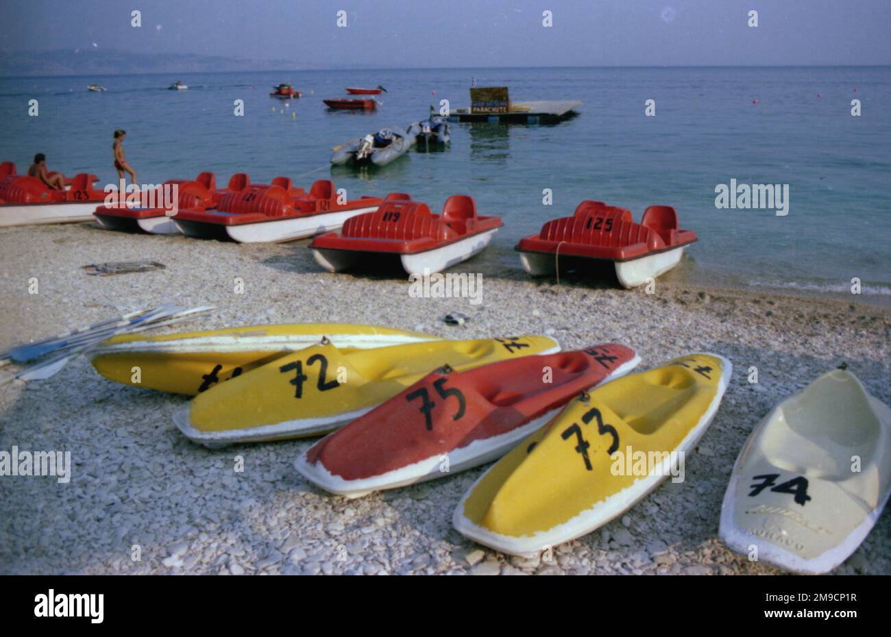 Brightly coloured red and yellow pedaloes on the beach at Corfu, Greece. Stock Photo