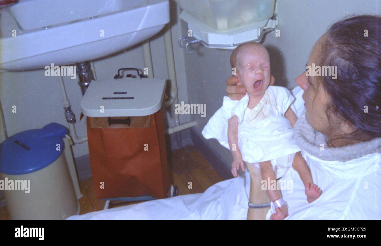 A premature baby girl is held by her mother at Redhill Hospital, Surrey ...